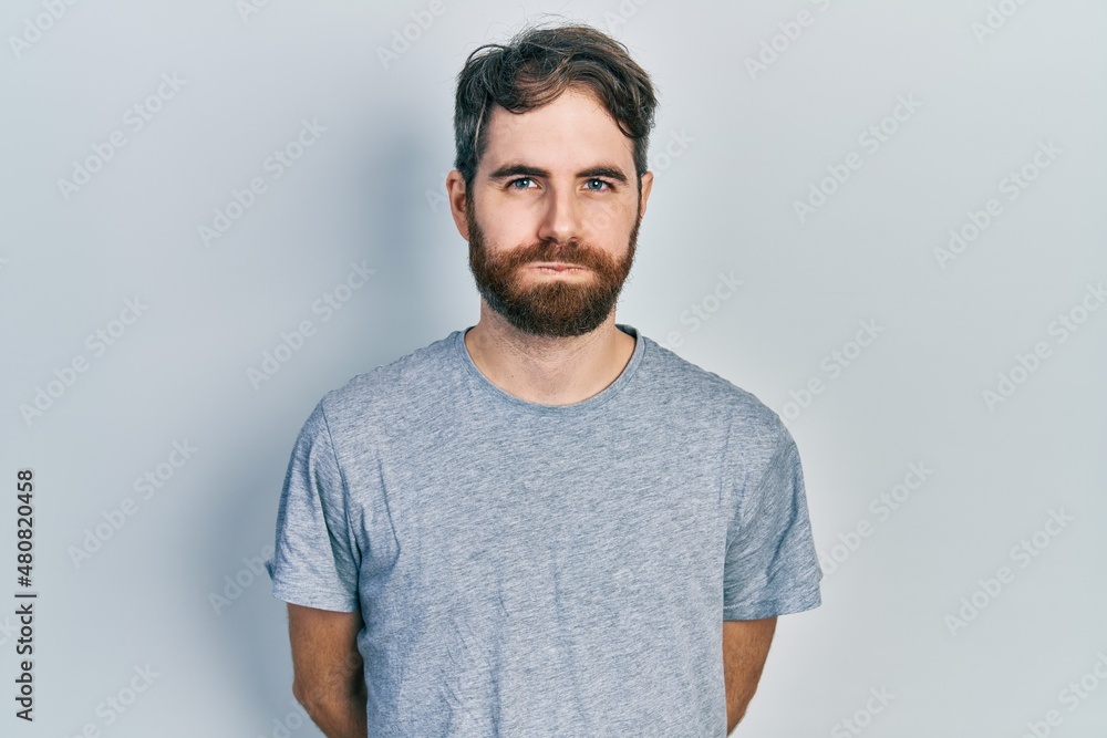 Caucasian man with beard wearing casual grey t shirt puffing cheeks with funny face. mouth inflated with air, crazy expression. Caucasian man with beard wearing casual grey t shirt puffing cheeks with funny face. mouth inflated with air, crazy expression.