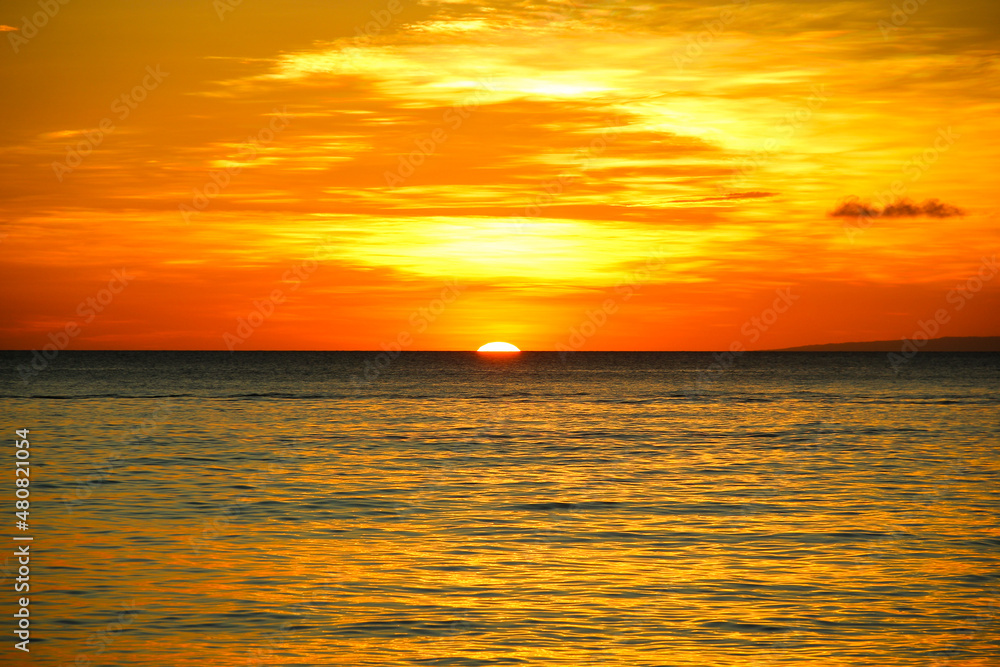 Sun going down on horizon at calm sea in Boracay island, Philippines. Perfect sunset under orange sky