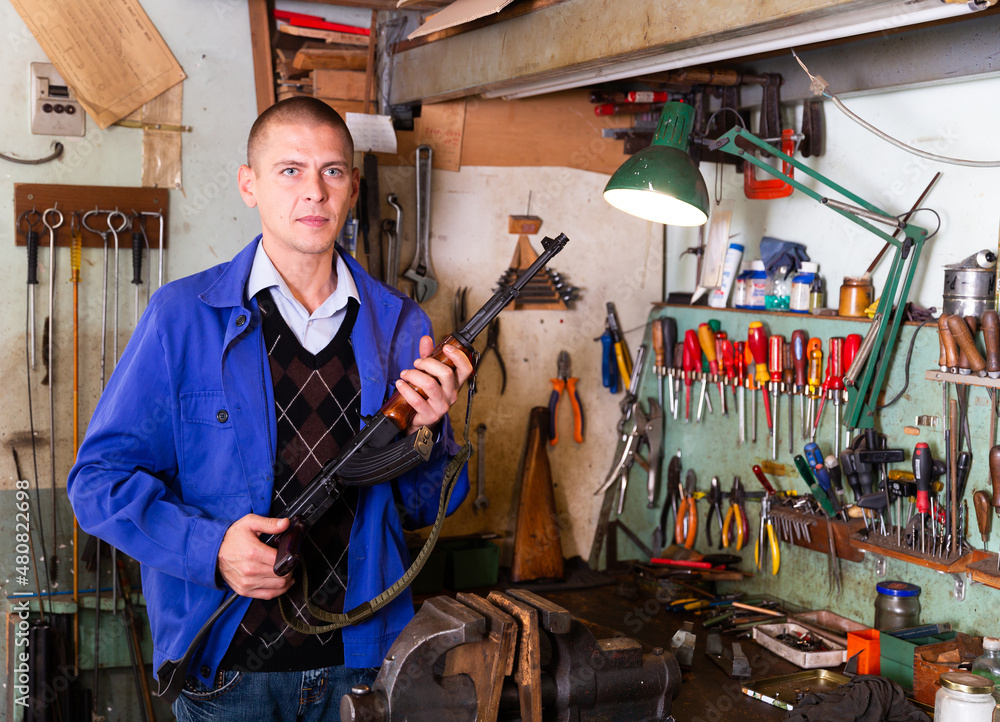 Gunsmith with Kalashnikov assault rifle in a weapons Stock