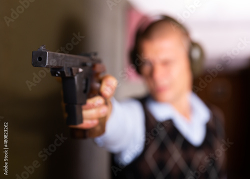 Closeup of smallbore sporting pistol in hand of man training in shooting range