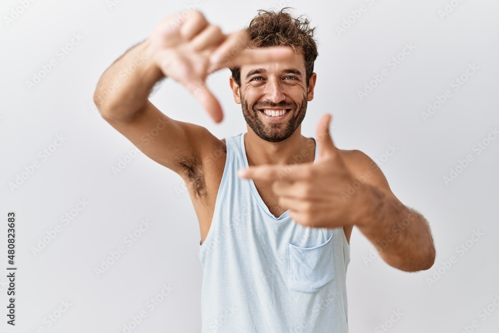 Young handsome man standing over isolated background smiling making frame with hands and fingers with happy face. creativity and photography concept. Young handsome man standing over isolated background smiling making frame with hands and fingers with happy face. creativity and photography concept.