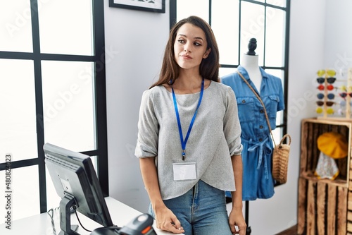 Young brunette woman working as manager at retail boutique smiling looking to the side and staring away thinking.