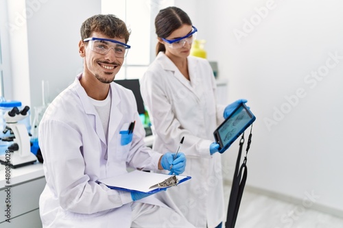 Man and woman partners wearing scientist uniform using touchpad with embryo image at laboratory photo