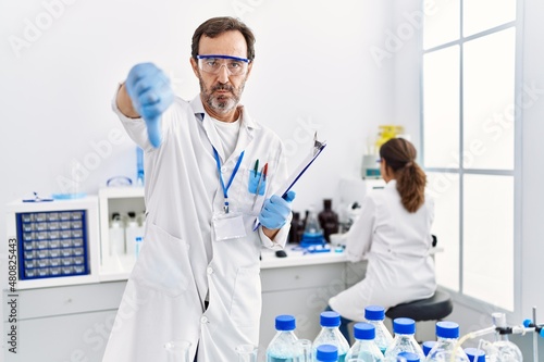 Middle age man working at scientist laboratory with angry face  negative sign showing dislike with thumbs down  rejection concept