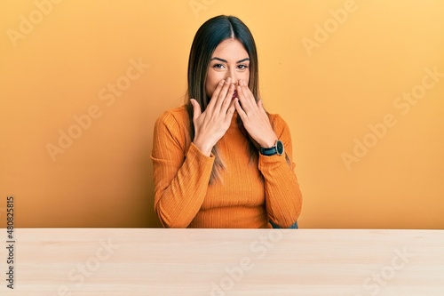 Schilderij op canvas Young hispanic woman wearing casual clothes sitting on the table laughing and em