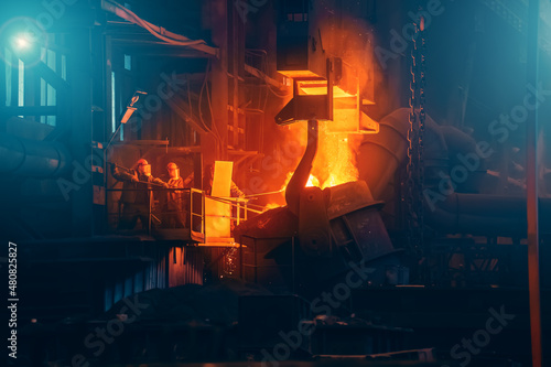 Iron casting in foundry. Metallurgical plant. Liquid metal pouring from ladle container into molds in blast furnace. Heavy metallurgy industry.