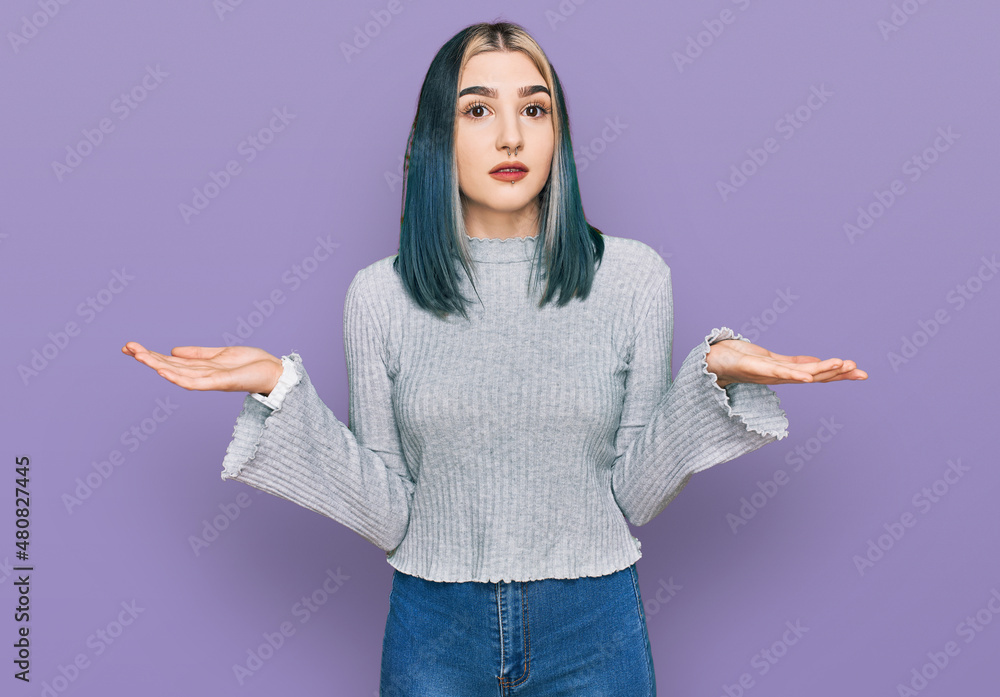 Young modern girl wearing casual sweater clueless and confused expression with arms and hands raised. doubt concept. Young modern girl wearing casual sweater clueless and confused expression with arms and hands raised. doubt concept.