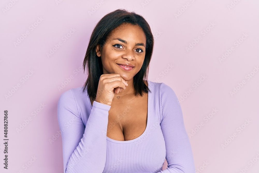 Young african american girl wearing casual clothes looking confident at the camera with smile with crossed arms and hand raised on chin. thinking positive. Young african american girl wearing casual clothes looking confident at the camera with smile with crossed arms and hand raised on chin. thinking positive.