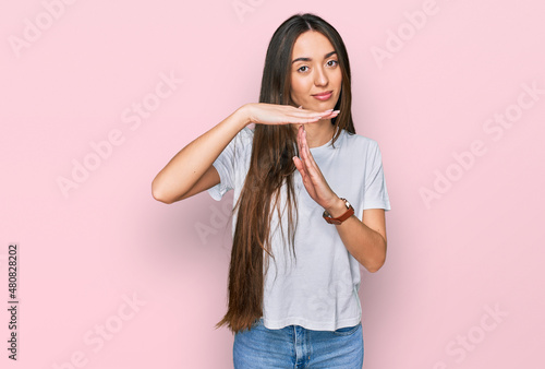 Young hispanic girl wearing casual white t shirt doing time out gesture with hands, frustrated and serious face
