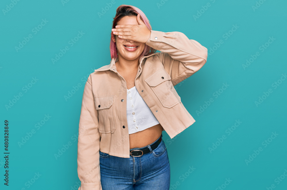 © Krakenimages.com - Hispanic woman with pink hair wearing casual clothes smiling and laughing with hand on face covering eyes for surprise. blind concept.