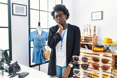 African young woman working as manager at retail boutique thinking looking tired and bored with depression problems with crossed arms.