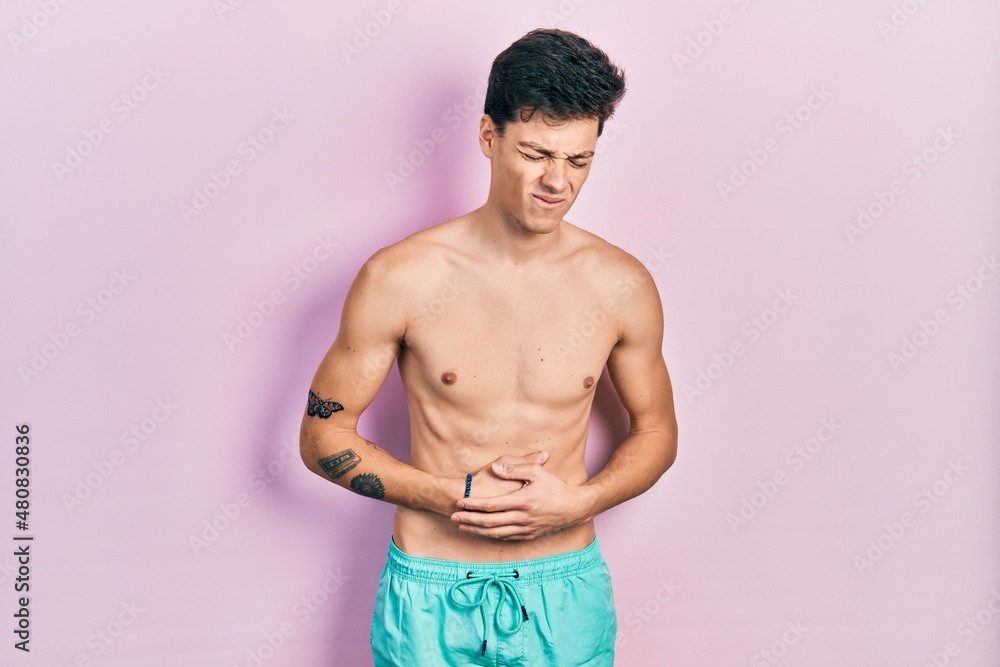 Fototapeta premium Young hispanic man wearing swimwear shirtless with hand on stomach because indigestion, painful illness feeling unwell. ache concept.
