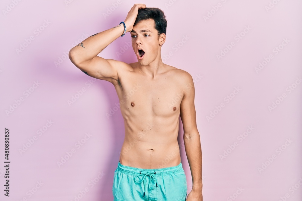 Fototapeta premium Young hispanic man wearing swimwear shirtless surprised with hand on head for mistake, remember error. forgot, bad memory concept.