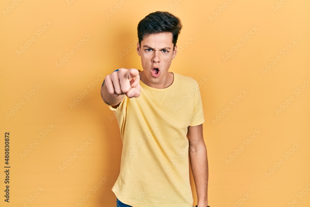 Young hispanic man wearing casual yellow t shirt pointing displeased and frustrated to the camera, angry and furious with you Young hispanic man wearing casual yellow t shirt pointing displeased and frustrated to the camera, angry and furious with you