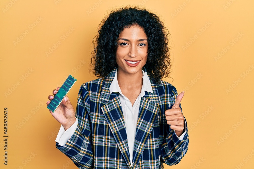 Young latin girl holding computer ram smiling happy and positive, thumb up doing excellent and approval sign Young latin girl holding computer ram smiling happy and positive, thumb up doing excellent and approval sign