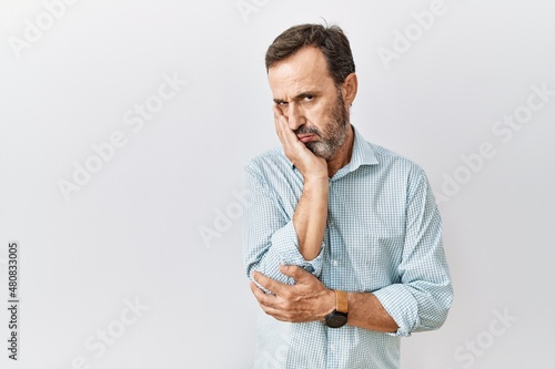 Middle age hispanic man with beard standing over isolated background thinking looking tired and bored with depression problems with crossed arms.