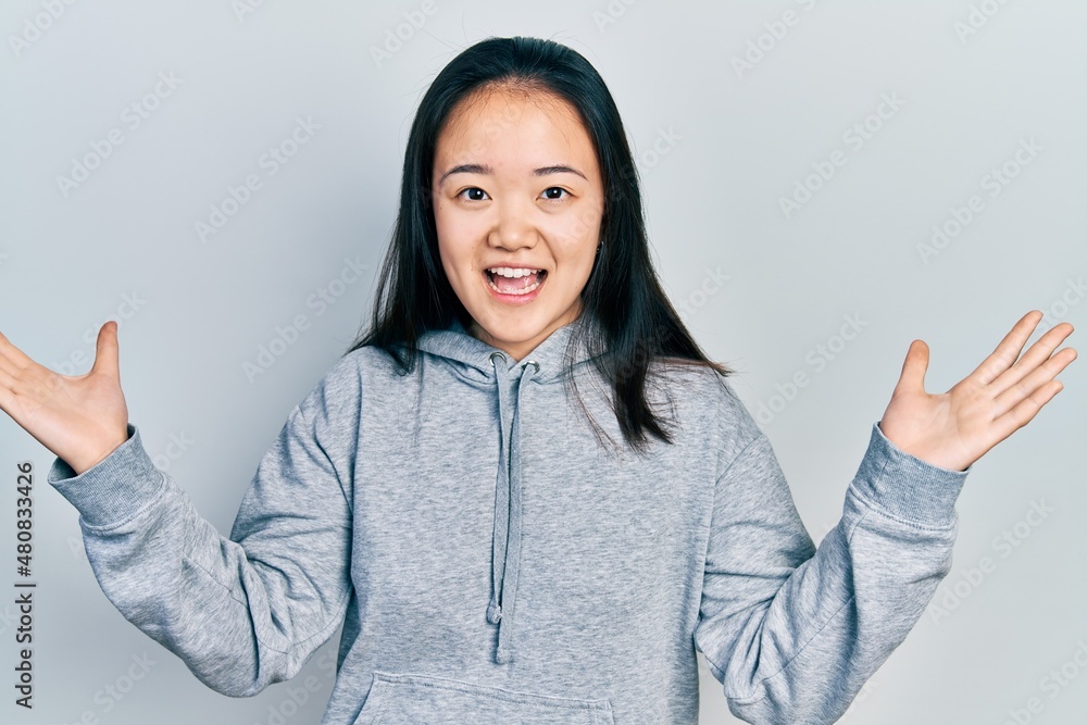 Young chinese girl wearing casual clothes celebrating victory with happy smile and winner expression with raised hands