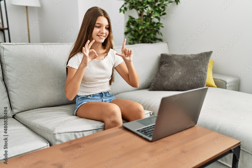 Adorable girl having video call communicating with deaf language sitting on sofa at home Adorable girl having video call communicating with deaf language sitting on sofa at home
