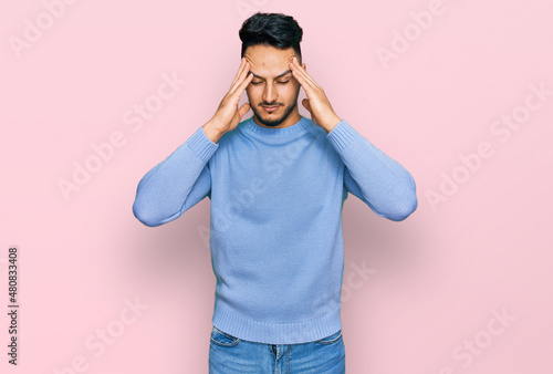 Young arab man wearing casual clothes suffering from headache desperate and stressed because pain and migraine. hands on head.