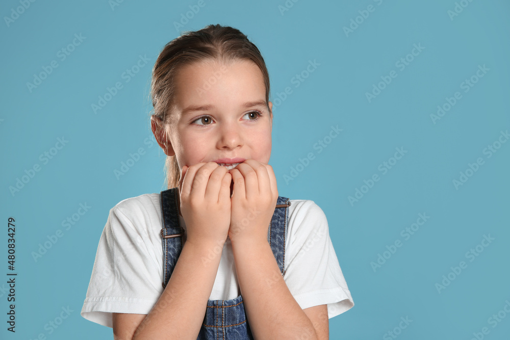 Cute little girl biting her nails on turquoise background. Space for text Cute little girl biting her nails on turquoise background. Space for text