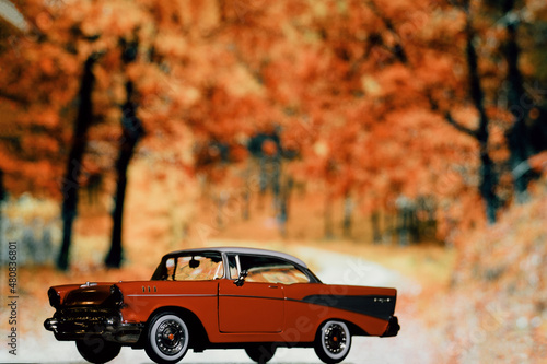Retro car toy model in front of the autumn forest background