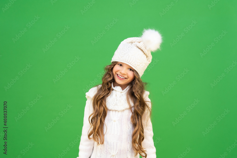 a little girl in a warm sweater and a winter hat on an isolated background. a child with curly hair in warm clothes and a joyful mood. a little girl in a warm sweater and a winter hat on an isolated background. a child with curly hair in warm clothes and a joyful mood.