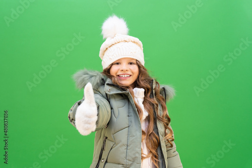 a child with a good mood in a winter jacket and hat. The little girl is glad of winter and warm clothes.  clothes for children in the cold season.