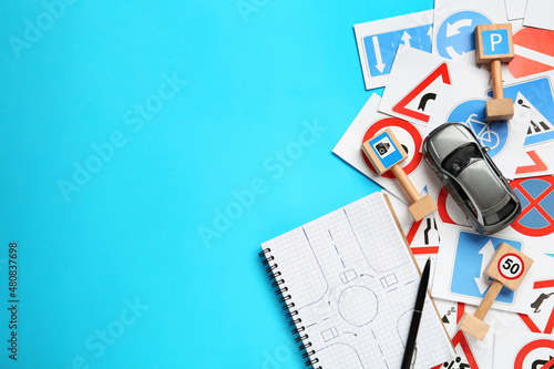 Canvas Many different road signs, notebook and toy car on light blue background, flat lay with space for text