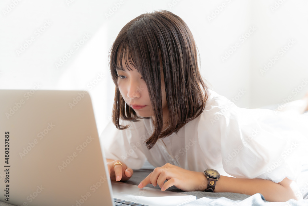うつ伏せでノートパソコンを開く女性 うつ伏せでノートパソコンを開く女性