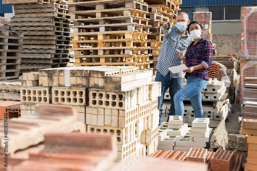 Man and woman in protective mask keep track of the number of bricks at the site of a hardware store