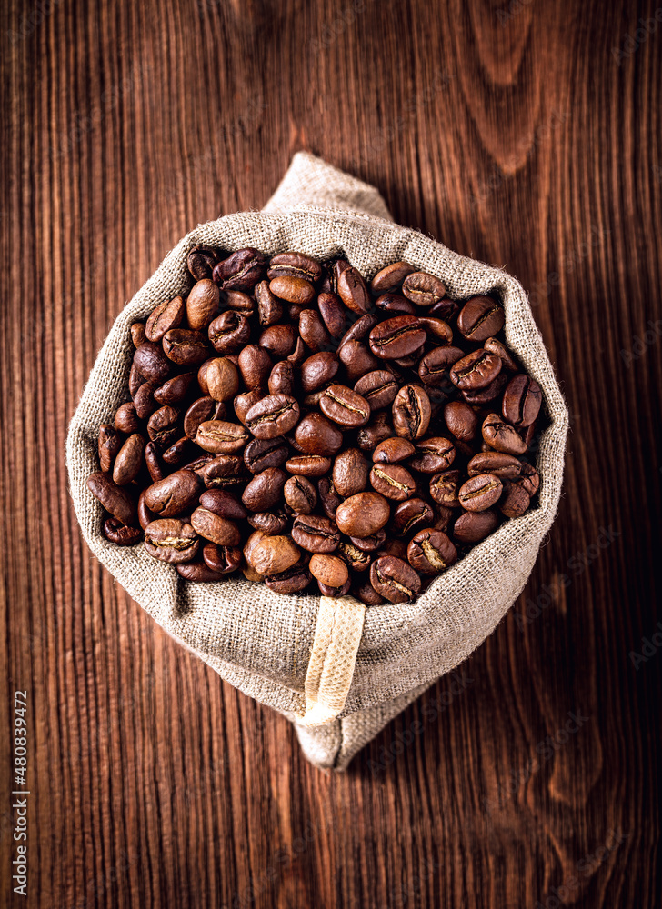 Burlap bag with coffee beans on wooden background Burlap bag with coffee beans on wooden background