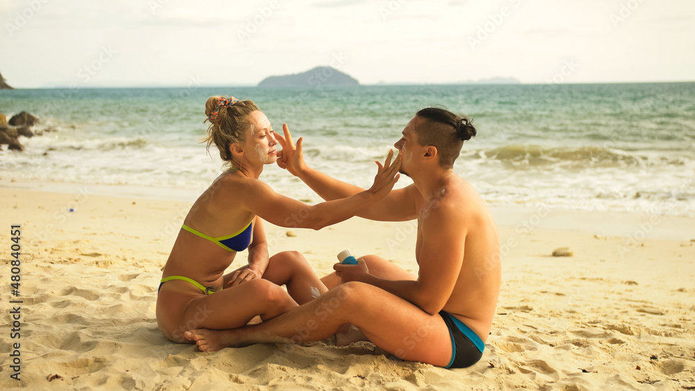Fototapeta premium Cute loving couple each other having sun block. Woman to put sun