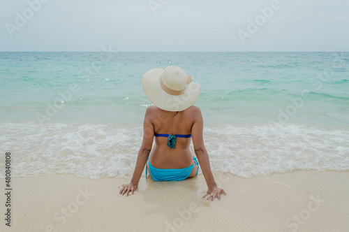 Espalda de mujer en traje de baño posando sentada en Playa Blanca Barú en Cartagena en Colombia © Josuhe
