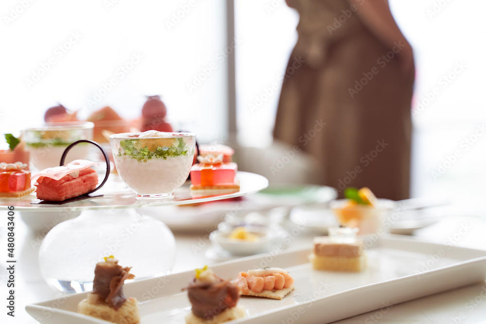 woman standing by window with assorted desserts on table woman standing by window with assorted desserts on table