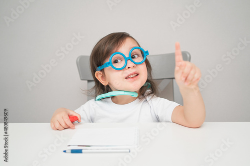 A small child in a doctor's costume. An artistic girl plays doctor. A child in glasses and a white T-shirt.