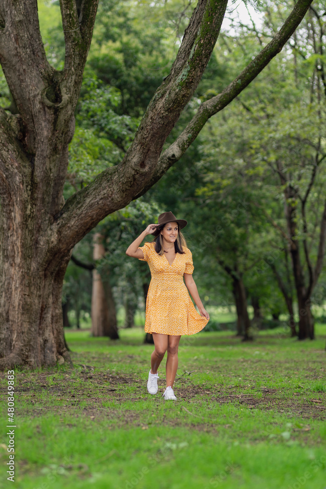 Young Mexican woman walking through the forest with a big tree in the background Young Mexican woman walking through the forest with a big tree in the background