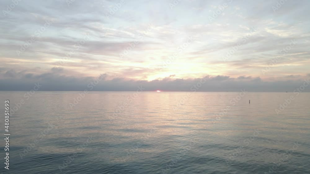 Low flight over water toward pink cloudy sunrise on ocean horizon Low flight over water toward pink cloudy sunrise on ocean horizon