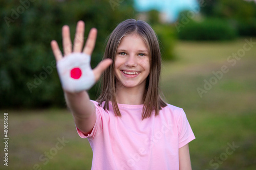 Kid girl show stop gesture with hands painted in Japan flag colors. Reopen school, Healthcare. Education abroad. Learn Japanese. Selective focus
