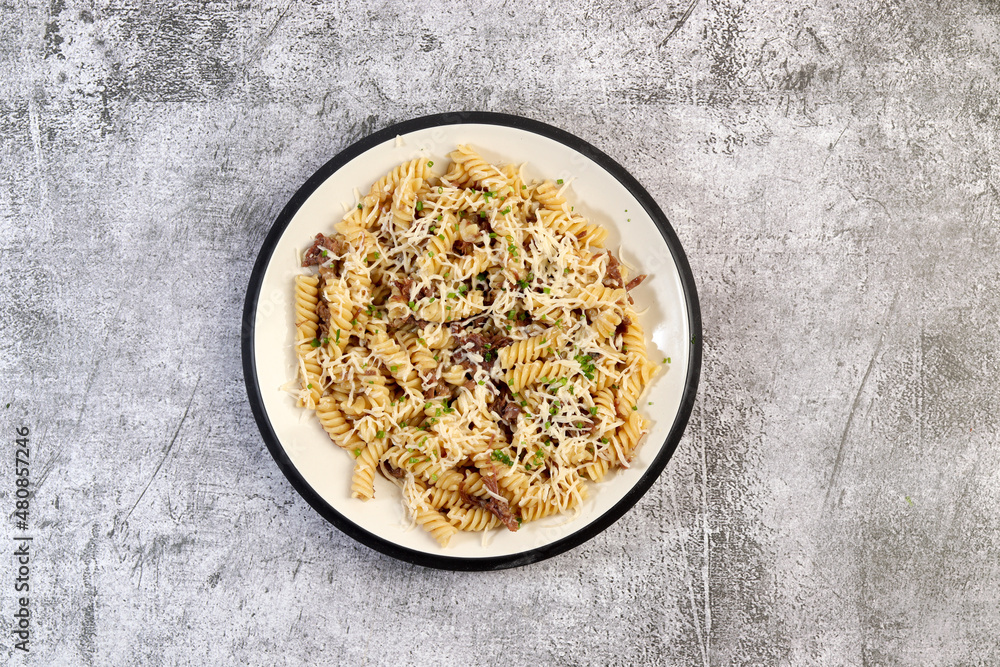 Pasta with beef stew and cheese on a round plate on a dark gray background. Top view, flat lay Pasta with beef stew and cheese on a round plate on a dark gray background. Top view, flat lay