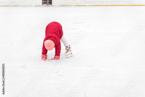 cute little girl in a hat with a bumbon on ice skates on a winter day photo