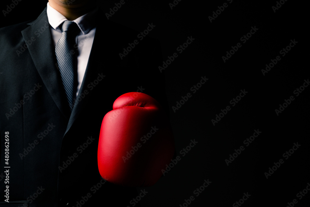 Businessman in red boxing gloves standing on black background, ready to fight business.