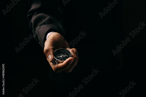 Compass in businessman hand to guide business direction standing black background, Marketing trends