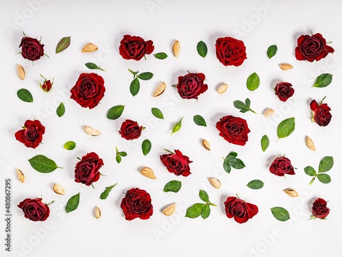 Floral pattern of burgundy rose buds, almonds and green leaves. Light background. flat lay