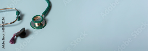 Graduation cap with stethoscope and numbers 2022 on blue background, closeup with copy space. Medical education concept.