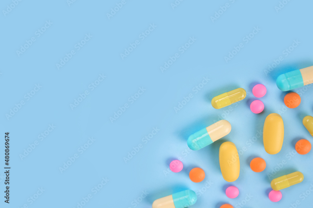 Assorted medicine pills, capsules and tablets on blue background with copy space. Immune system vitamins and supplemets. Flat lay