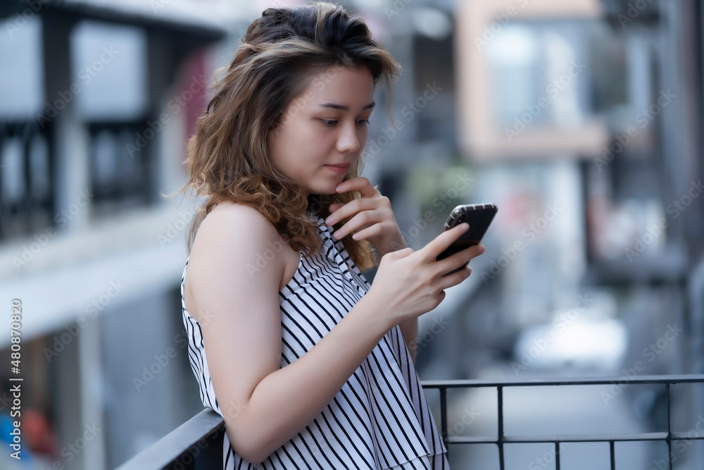 Fototapeta premium The young woman is checking media on her mobile phone during work from home