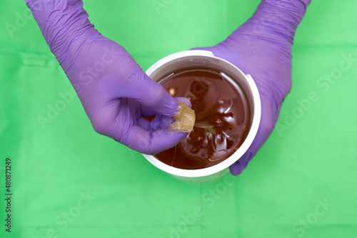 thick sugar paste wax in the hands of a master for hair removal with sugar caramel depilation photo