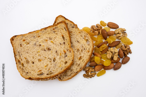 Slices of multigrain bread with almonds, walnuts and raisins. Healthy diet. Isolated top view on white background.