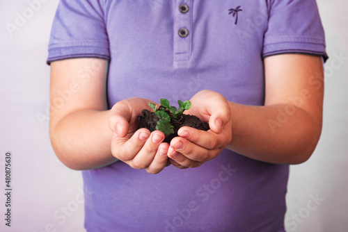 Portrait of handsome young teen boy holding green plant as a symbol of lean attitude to nature on white background