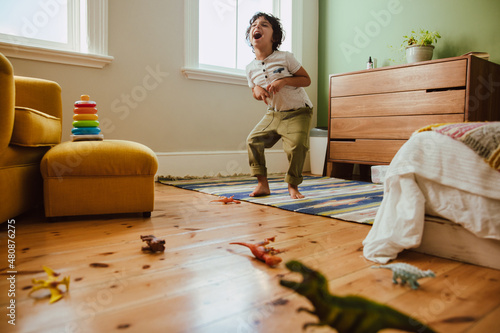 Creative young boy mimicking a t-rex dinosaur in his play area